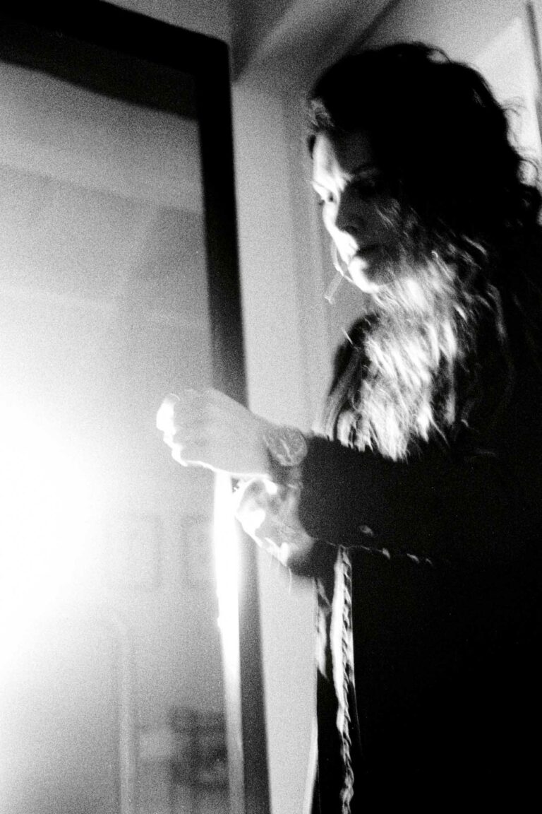 vue de profil d'une femme , cigarette à la bouche et qjui remet sa montre en place avec un léger flou noir et blanc et une lumière forte qui arrive de côté