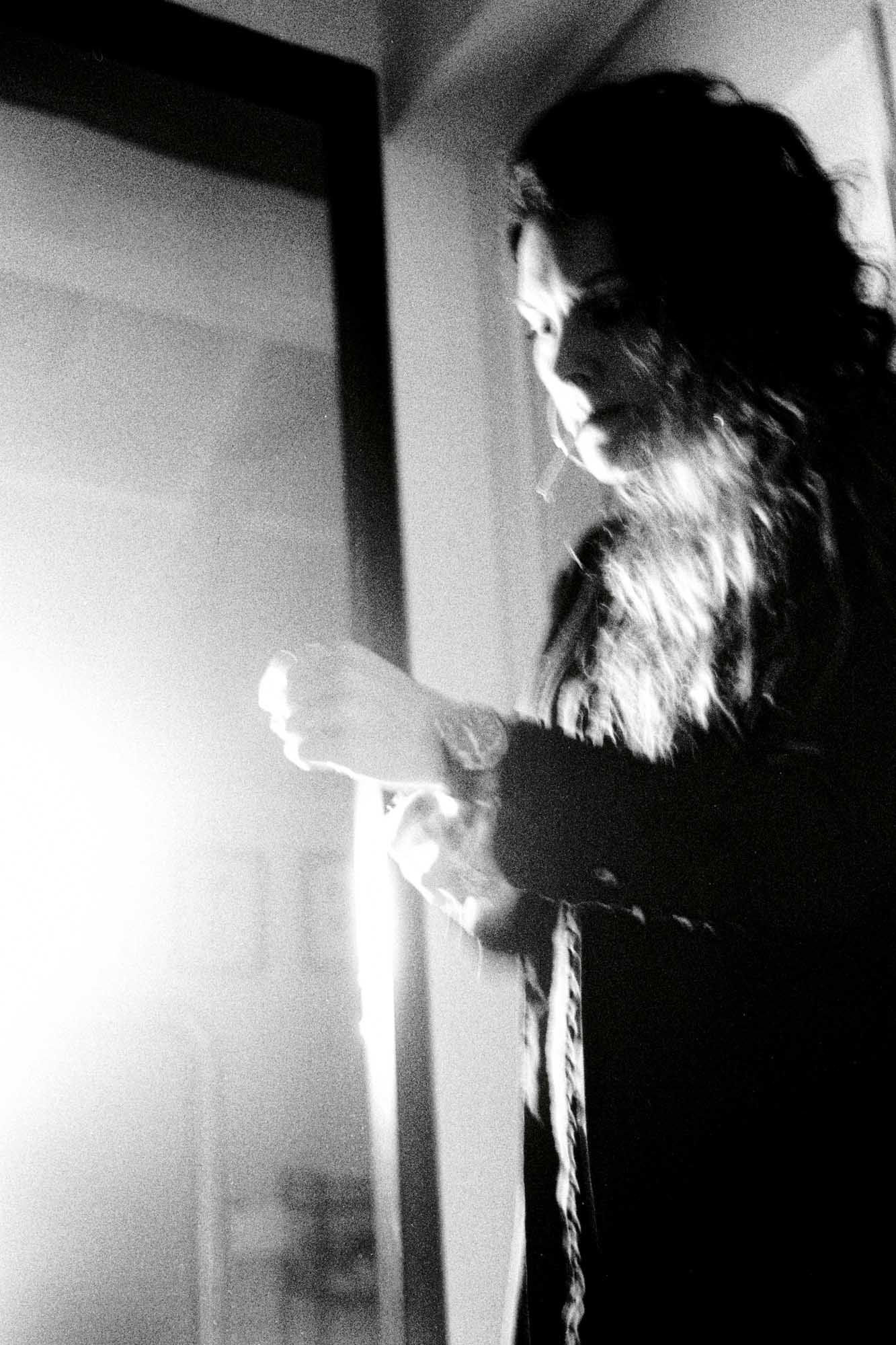 vue de profil d'une femme , cigarette à la bouche et qjui remet sa montre en place avec un léger flou noir et blanc et une lumière forte qui arrive de côté