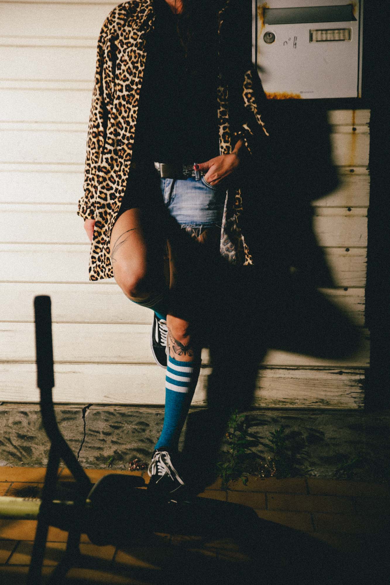 photographie couleur , on distingue une femme, main dans la poche avec un haut leopard et un bMX au sol ainsi que de jolis ombres