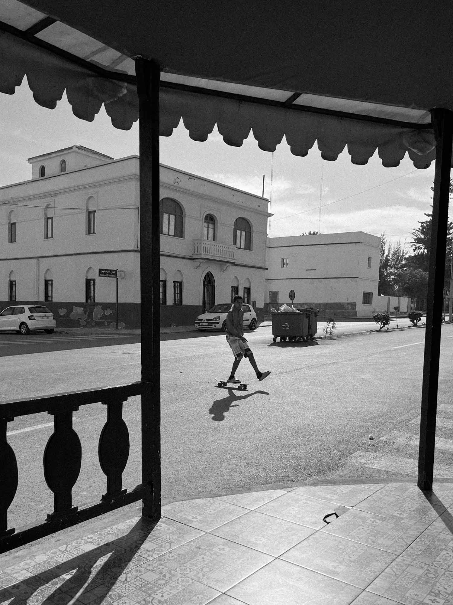 photographie argentique noir et blanc d'un skateur au maroc qui traverse la route en tongue et me regarde