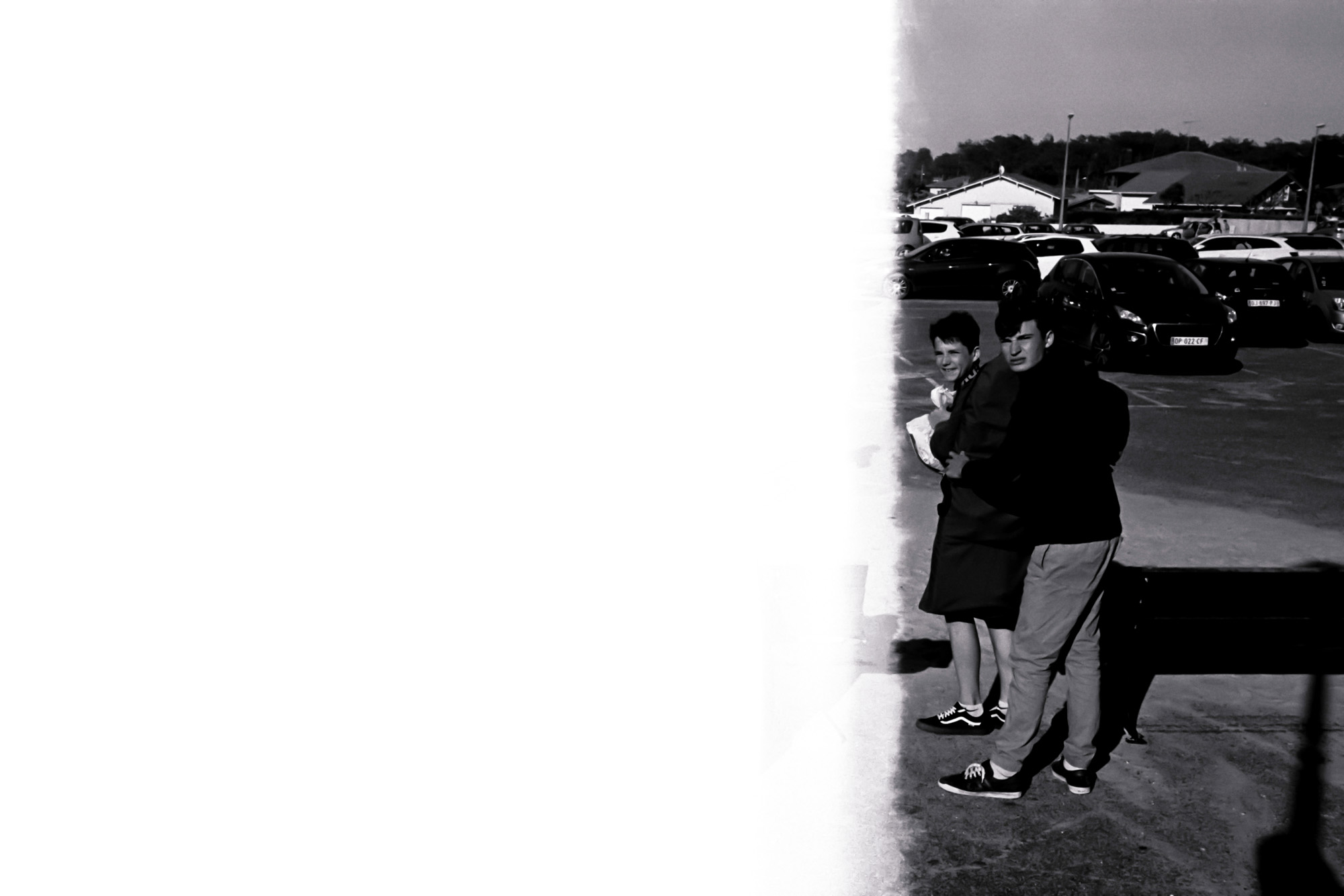 deux jeunes enfants me regardent prendre la photo alors qu"'ils marchent sur un parking