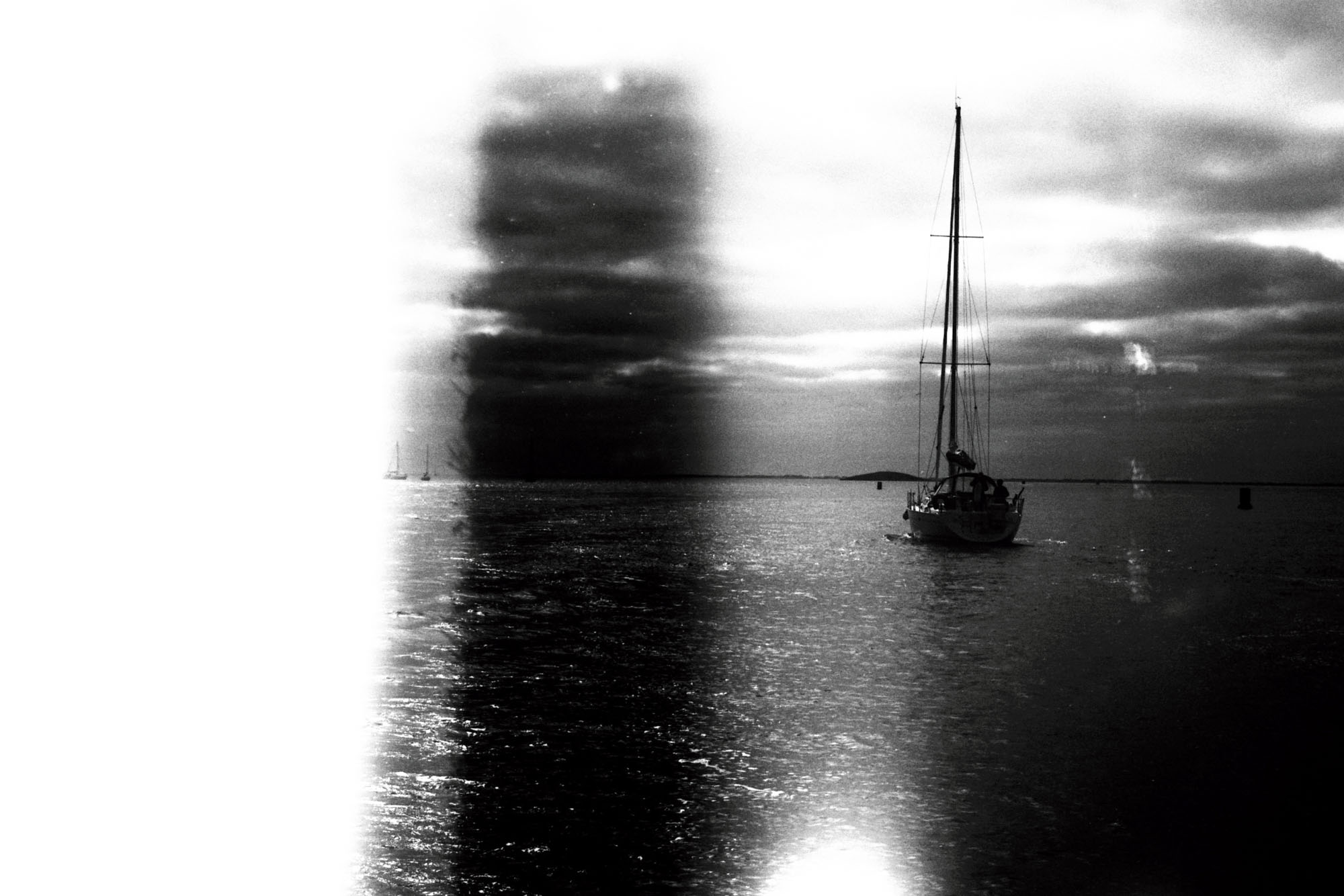 un bateau à voile navigue, on distingue des bnandes verticakes dues à un erreur de manipulation de la pellicuke argentique