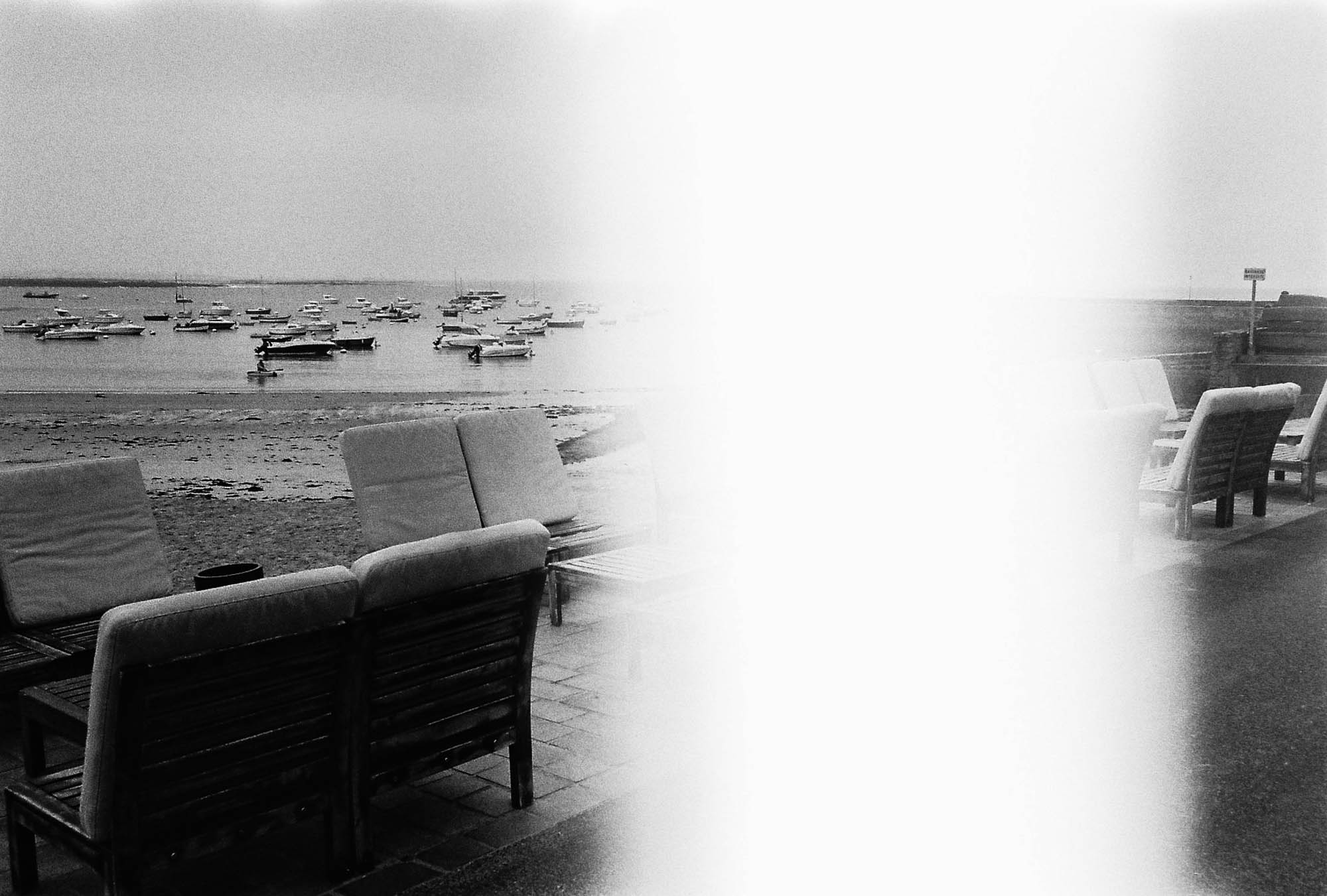 photographie argentique coupée en deux par une bande blanche avec des bateaux dansun port en bretagne et des salons en premier plan