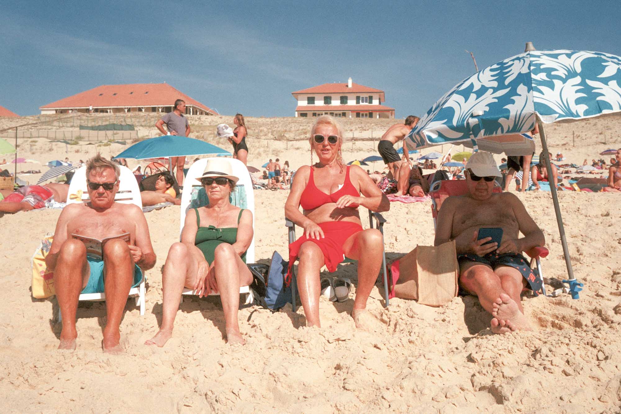 une bande de retraités sous parasol et installés sur des chaises en ligne me font face alors que je le les prends en photo. un lit, l'autre est sur son téléphone