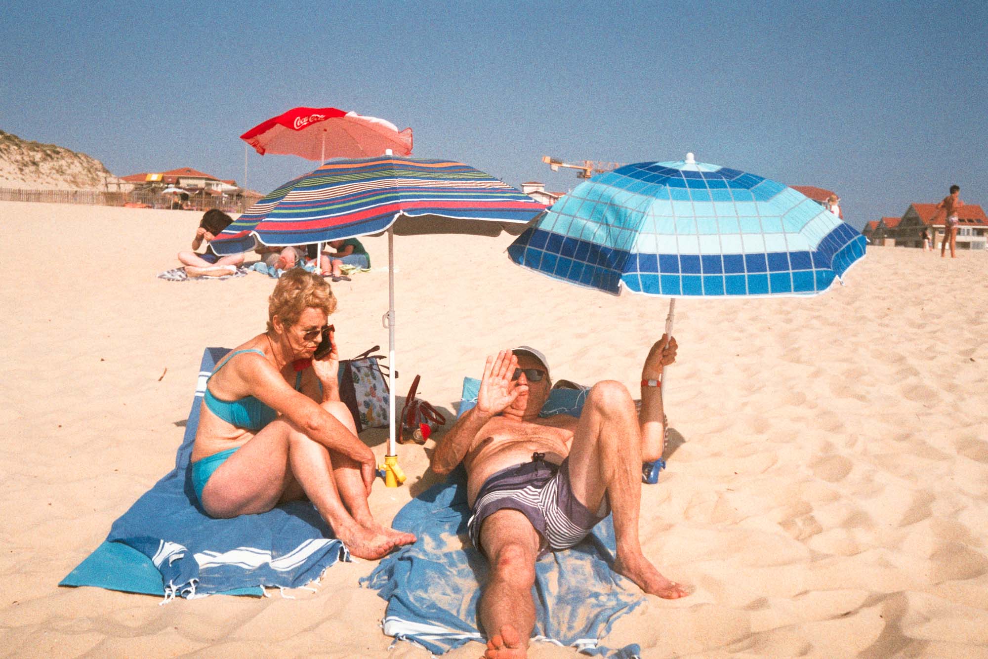 un couple agé est allongé sur le sable de la plage de Vieux-Boucau, l'homme me dit non de la main et sa femme est au téléphone, sous un parasol