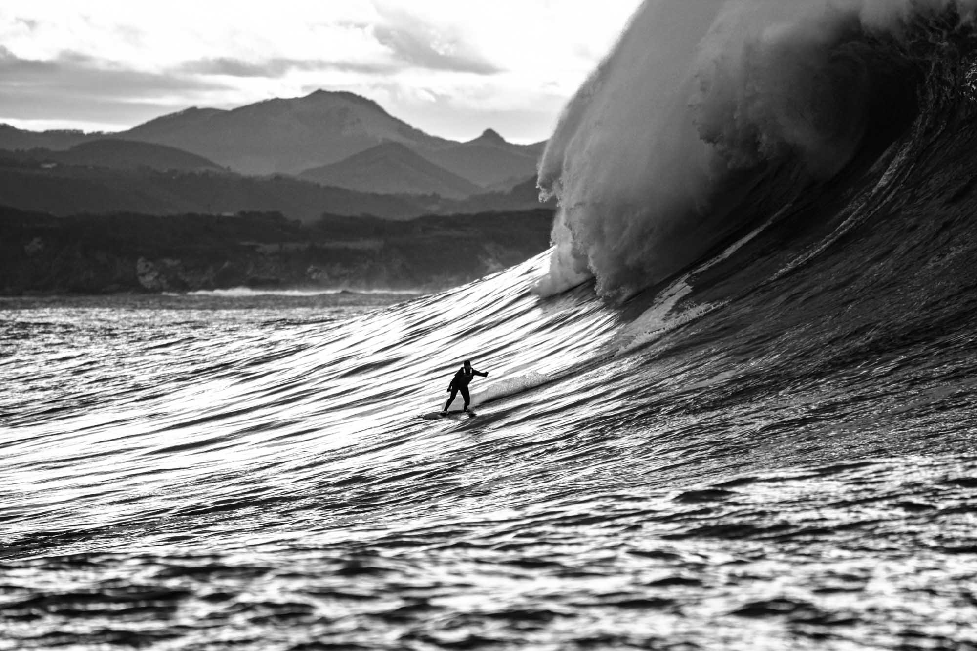 surfeur en gros plan qui descend la vague géante de belharra, photographie noir et blanc