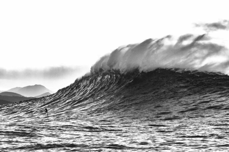 on distingue une vague de profil de 15 mètres et un surfeur en bas, photographie de belharra au pays-basque