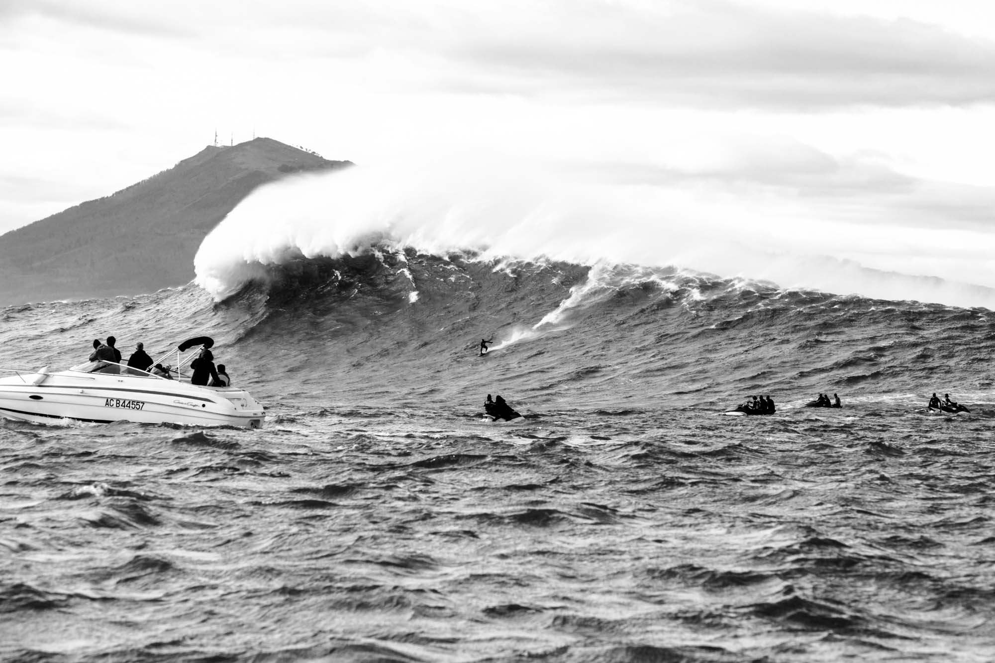 scéne de surf à belharra avec un surfeur, les jets et les bateaux, en noir et blanc, on voir tout le monde sur l'eau présent et la montage la rune en fond