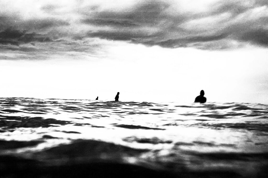 Trois silhouettes de surfeurs alignées dans l'eau, tirage d'art argentique noir et blanc "LineUp", MonVilain