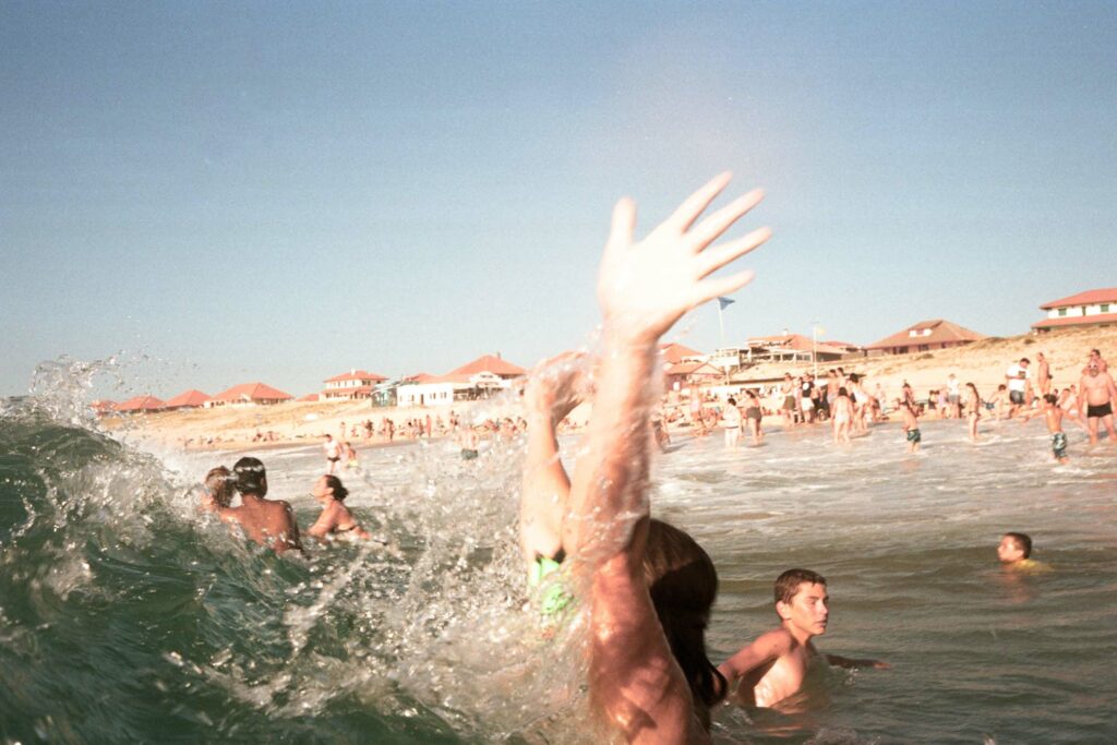 Main levée éclaboussant au premier plan d'une vague, tirage d'art argentique couleur "Youpi Les Vacances", MonVilain