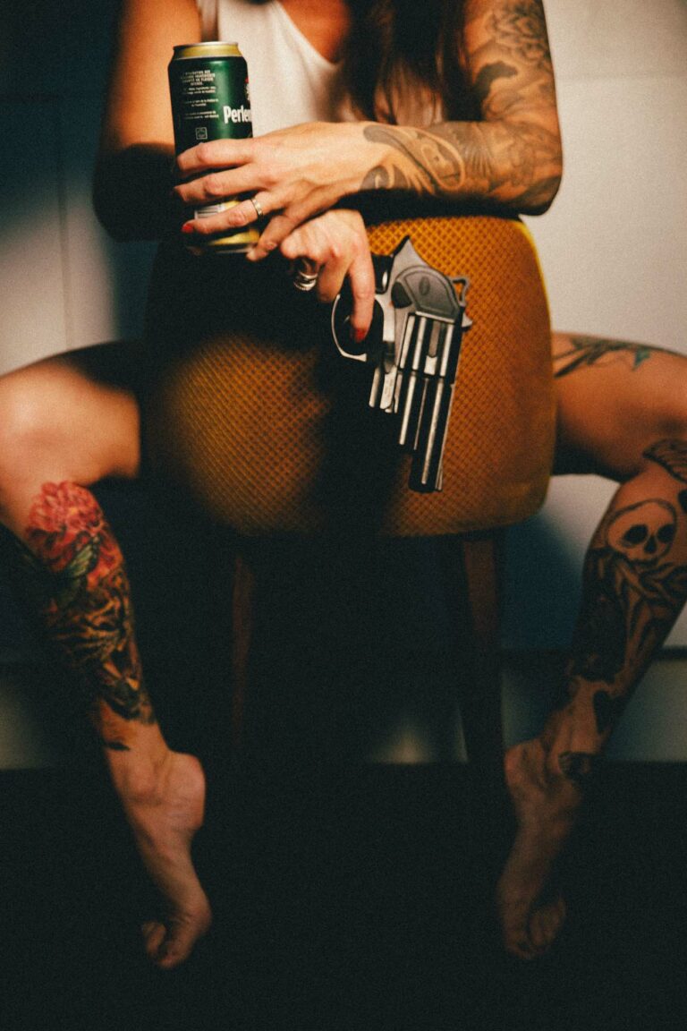 une femme tatouée porrte un pistolet à l main