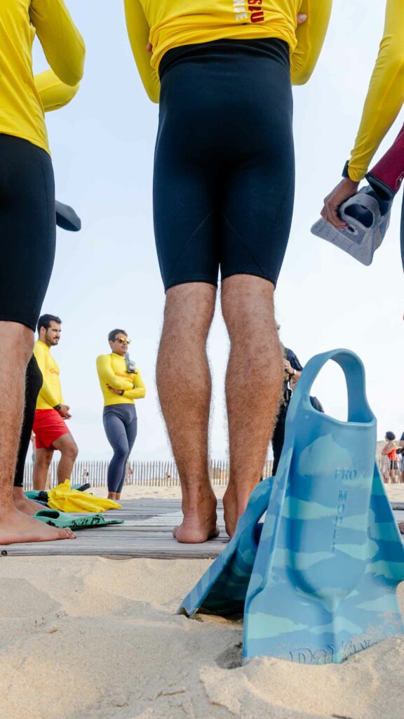 Nageurs-sauveteurs en combinaison, palmes à la main, avant l'exercice sur la plage