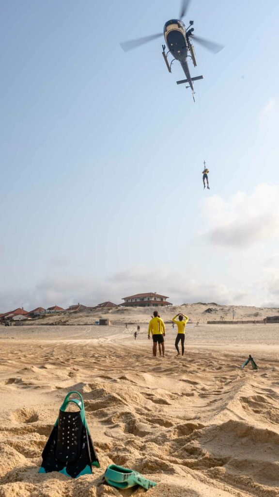 Vue large d'un hélitreuillage, nageurs-sauveteurs observant depuis la plage