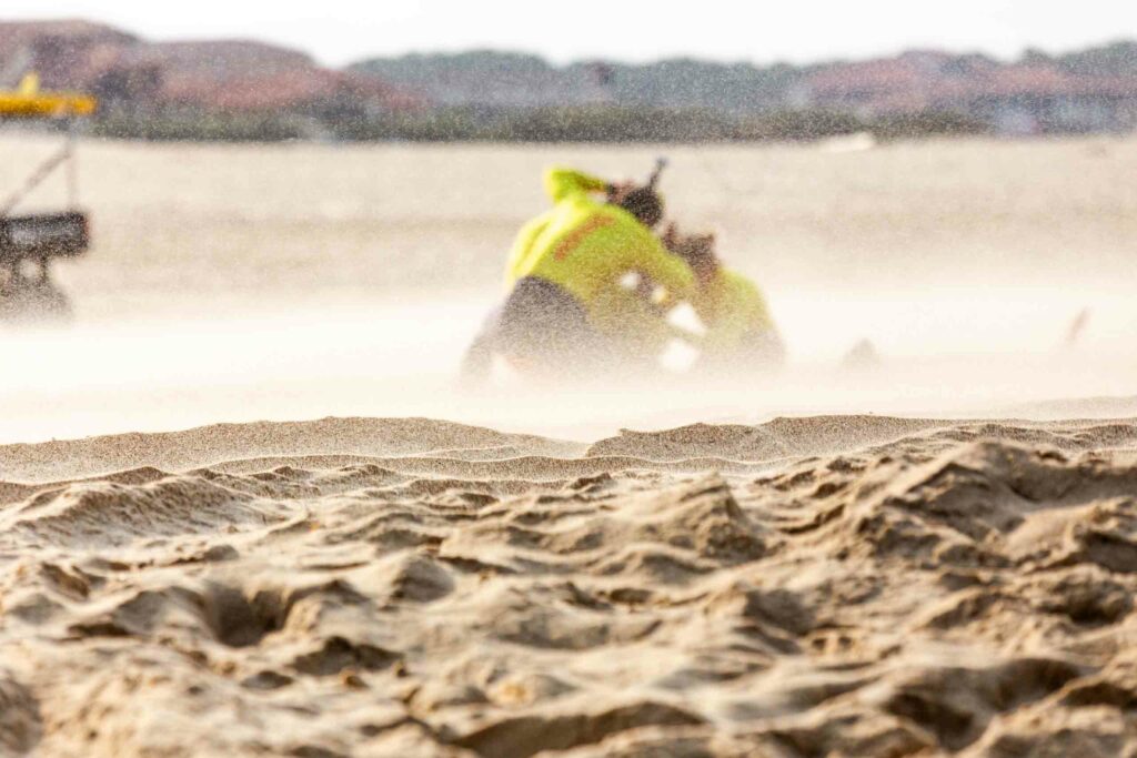 Quad de secours des nageurs-sauveteurs roulant dans un nuage de sable